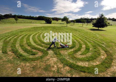 Photo de Roger Bamber : 25 juin 2005 : Park Art.. L'artiste Chris Drury tond son 'labyrinthe des doigts', une impression de 38 mètres X 30 mètres de son empreinte digitale, tondue dans l'herbe du parc à Stanmer Park, Brighton. L'œuvre, l'une des deux, l'autre à Hove Park, est commandée par l'initiative Brighton & Hove Arts 'Making a Difference' financée par l'argent de la loterie de la Commission du millénaire et du Conseil des arts. tirer le meilleur parti de la sécheresse - soulignant le contraste dans l'herbe brune desséchée un homme est allé tondre l'eau ; jardin ; jardinage ; horticulture ; art; artiste ; Banque D'Images