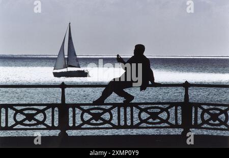 Althea Thomas mange sa crème glacée préférée sur le front de mer de Hove alors qu'un yacht solitaire navigue devant. Prise dans le cadre d'une série de photos des résidents de Brighton et Hove pour appuyer la demande de la ville pour obtenir le statut de ville en 2000. Banque D'Images