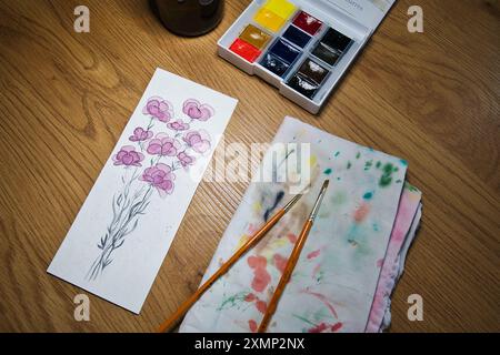 Un espace de travail d'artiste accueillant avec une peinture à l'aquarelle vibrante de fleurs en cours. Illustration, créativité, techniques artistiques, artistiques. Banque D'Images