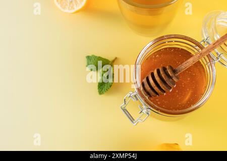 Un pot de miel avec une louche de miel avec des feuilles de menthe et des tranches de citron. Banque D'Images