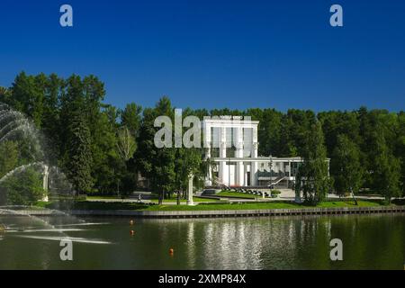 Moscou, Russie, 20 juin 2024. VDNH, Musée du Cinéma. Un étang ou un lac en face d'un manoir blanc ou d'un bâtiment entouré d'arbres verts et d'herbe. Q élevé Banque D'Images