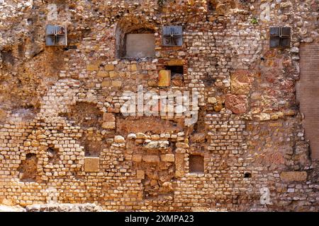 Fragment de mur texturé avec divers éléments en pierre et ouvertures Banque D'Images