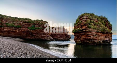 Un empilement de grès dans la baie de Ladram près de Sidmouth dans le sud-est du Devon, capturé au lever du soleil en juillet. Banque D'Images