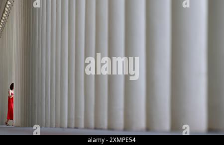 Wiesbaden, Allemagne. 29 juillet 2024. Une femme en robe rouge disparaît entre les colonnes de la colonnade du théâtre, prise vers 1838/39 (prise avec une vitesse d'obturation plus lente). Crédit : Arne Dedert/dpa/Alamy Live News Banque D'Images