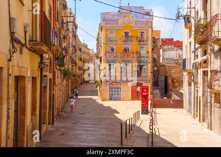 Tarragone, Espagne - 15 juillet 2024 : rue pittoresque bordée de bâtiments dynamiques et d'une fresque colorée, représentant la culture artistique et le charme urbain o Banque D'Images