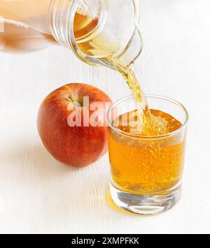 Jus de pomme versé de la verseuse dans un verre Banque D'Images