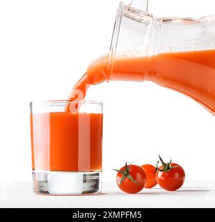 Jus de tomate versé de la cruche dans un verre Banque D'Images