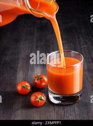 Jus de tomate versé de la cruche dans un verre Banque D'Images