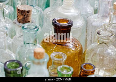 Grand groupe de petites bouteilles en verre vides, vieillies et poussiéreuses. Fond vintage abstrait. Banque D'Images