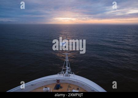 Le bateau de croisière navigue vers le coucher du soleil. Drapeau blanc Bow of Ship, coucher le soleil sur l'horizon. Voyage d'aventure dans les eaux bleues chaudes et claires Banque D'Images