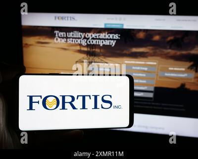 Personne tenant un téléphone intelligent avec le logo de l'entreprise canadienne de services publics d'électricité Fortis Inc devant le site Web. Concentrez-vous sur l'affichage du téléphone. Banque D'Images