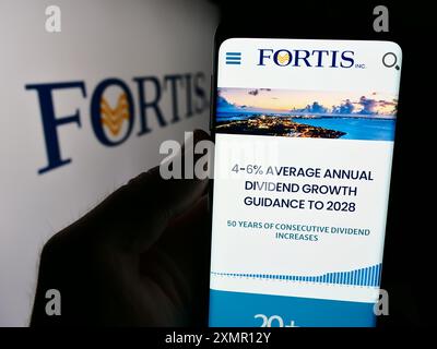 Personne tenant un téléphone cellulaire avec la page Web de la compagnie canadienne de services publics d'électricité Fortis Inc. devant le logo. Concentrez-vous sur le centre de l'écran du téléphone. Banque D'Images