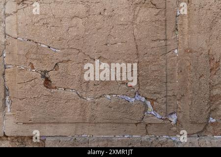 Notes de papier avec bénédictions et prières à l'intérieur des fissures du mur occidental. Le mur occidental, également connu sous le nom de mur des lamentations à l'Ouest et mur d'Al Buraq dans l'Islam, est une destination de pèlerinage pour les croyants juifs. Situé dans la vieille ville de Jérusalem, il fait partie du mur de soutènement du Mont du Temple. Une cloison métallique divise la zone en deux : les hommes à gauche et les femmes à droite. Tout au long de la journée, les croyants juifs visitent le site pour prier, lire les livres sacrés de la Torah et laisser une note de papier à l’intérieur des fissures du mur. Toute la zone est surveillée par des soldats israéliens. Banque D'Images