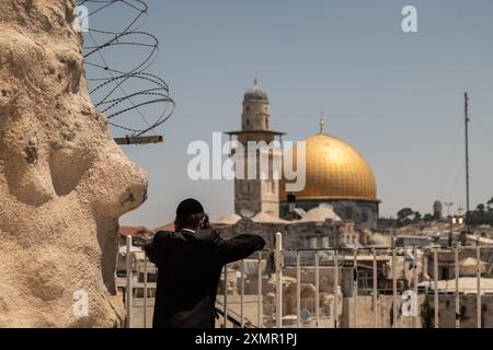 Un adorateur juif regarde le Dôme du Rocher et le mur occidental depuis une terrasse de la vieille ville. Le mur occidental, également connu sous le nom de mur des lamentations à l'Ouest et mur d'Al Buraq dans l'Islam, est une destination de pèlerinage pour les croyants juifs. Situé dans la vieille ville de Jérusalem, il fait partie du mur de soutènement du Mont du Temple. Une cloison métallique divise la zone en deux : les hommes à gauche et les femmes à droite. Tout au long de la journée, les croyants juifs visitent le site pour prier, lire les livres sacrés de la Torah et laisser une note de papier à l’intérieur des fissures du mur. Toute la zone est surveillée par ISR Banque D'Images