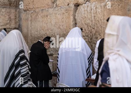 26 juillet 2024, Jérusalem, Israël : les fidèles juifs prient du côté des hommes du mur Occidental. Le mur occidental, également connu sous le nom de mur des lamentations à l'Ouest et mur d'Al Buraq dans l'Islam, est une destination de pèlerinage pour les croyants juifs. Situé dans la vieille ville de Jérusalem, il fait partie du mur de soutènement du Mont du Temple. Une cloison métallique divise la zone en deux : les hommes à gauche et les femmes à droite. Tout au long de la journée, les croyants juifs visitent le site pour prier, lire les livres sacrés de la Torah, et laisser une note de papier à l’intérieur des fissures du wallâ€™s. Toute la zone est surveillée par des soldats israéliens Banque D'Images