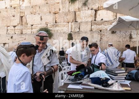 26 juillet 2024, Jérusalem, Israël : les fidèles juifs se préparent pour une prière au côté des hommes du mur Occidental. Le mur occidental, également connu sous le nom de mur des lamentations à l'Ouest et mur d'Al Buraq dans l'Islam, est une destination de pèlerinage pour les croyants juifs. Situé dans la vieille ville de Jérusalem, il fait partie du mur de soutènement du Mont du Temple. Une cloison métallique divise la zone en deux : les hommes à gauche et les femmes à droite. Tout au long de la journée, les croyants juifs visitent le site pour prier, lire les livres sacrés de la Torah, et laisser une note de papier à l’intérieur des fissures du wallâ€™s. Toute la zone est surveillée par Banque D'Images