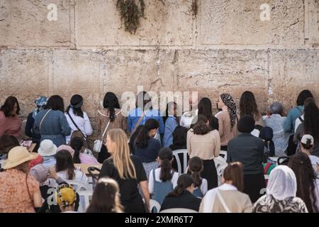 Les adorateurs juifs prient du côté des femmes du mur occidental. Le mur occidental, également connu sous le nom de mur des lamentations à l'Ouest et mur d'Al Buraq dans l'Islam, est une destination de pèlerinage pour les croyants juifs. Situé dans la vieille ville de Jérusalem, il fait partie du mur de soutènement du Mont du Temple. Une cloison métallique divise la zone en deux : les hommes à gauche et les femmes à droite. Tout au long de la journée, les croyants juifs visitent le site pour prier, lire les livres sacrés de la Torah et laisser une note de papier à l'intérieur des fissures du mur. Toute la zone est surveillée par des soldats israéliens. Banque D'Images