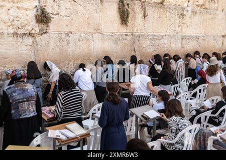 Les adorateurs juifs prient du côté des femmes du mur occidental. Le mur occidental, également connu sous le nom de mur des lamentations à l'Ouest et mur d'Al Buraq dans l'Islam, est une destination de pèlerinage pour les croyants juifs. Situé dans la vieille ville de Jérusalem, il fait partie du mur de soutènement du Mont du Temple. Une cloison métallique divise la zone en deux : les hommes à gauche et les femmes à droite. Tout au long de la journée, les croyants juifs visitent le site pour prier, lire les livres sacrés de la Torah et laisser une note de papier à l'intérieur des fissures du mur. Toute la zone est surveillée par des soldats israéliens. Banque D'Images