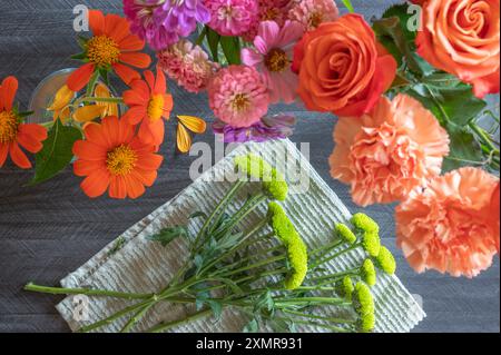 Fleurs de chrysanthum vert pour un arrangement floral entouré de fleurs oranges et roses. Banque D'Images