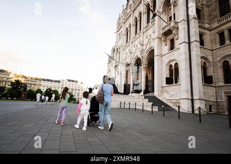 Famille profitant d'une promenade devant un bâtiment historique dans une place de la ville européenne. Parents et enfants passent du temps de qualité ensemble. Banque D'Images