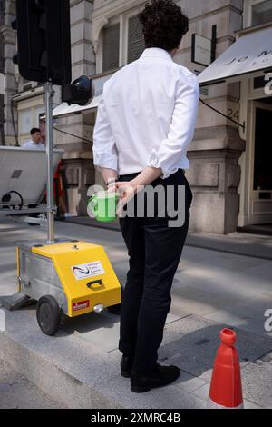 Un employé de la ville tient son conteneur de repas derrière son dos dans la City de Londres alias le Square Mile, le quartier financier de la capitale, le 29 juillet 2024, à Londres, en Angleterre. Banque D'Images