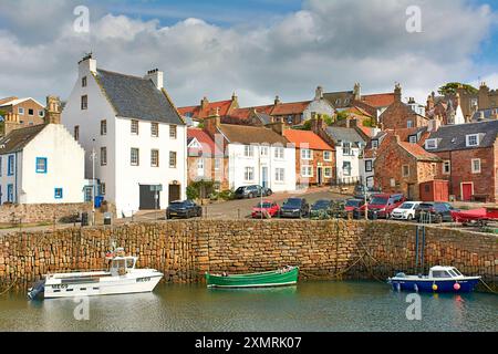 Crail Fife Écosse ciel bleu et nuages sur les pierres des murs du port les maisons et les bateaux de pêche amarrés en été Banque D'Images