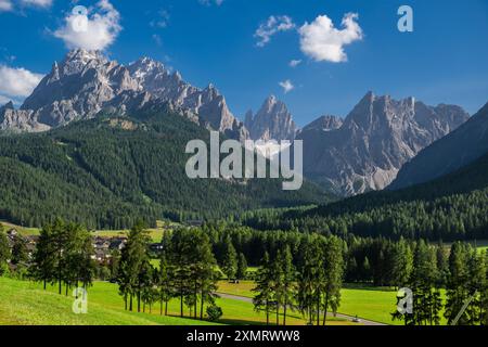 Sexten, Italie les sommets imposants des Dolomites s'élèvent majestueusement contre un ciel bleu éclatant, parsemé de nuages moelleux. Vallées verdoyantes et denses fo Banque D'Images