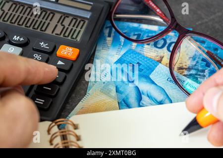 Francs suisses, analyse financière, comptabilité d'entreprise, calcul fiscal, concept d'entreprise financière. Suisse argent avec une calculatrice, main Banque D'Images