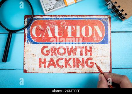 Concept de Growth Hacking. Signe d'avertissement avec texte sur le bureau en bois bleu. Banque D'Images