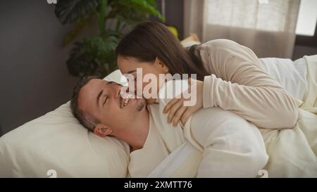 Un couple aimant partage un moment affectueux ensemble dans le confort de leur chambre. Banque D'Images