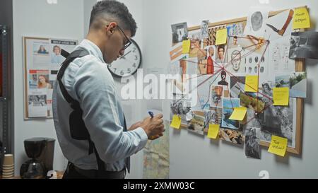 Un homme analyse des indices sur un panneau de liège dans le bureau d'un détective, suggérant une enquête en cours. Banque D'Images