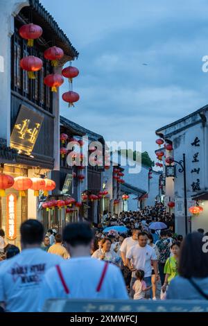 suzhou, Chine - 10 juin 2024 : Une rue animée à Suzhou, Chine, ornée de lanternes rouges, remplie de gens qui profitent de la soirée. Banque D'Images