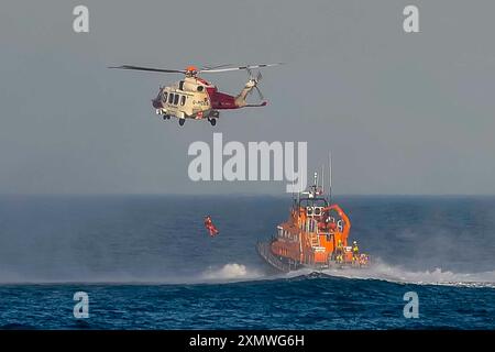 Weymouth, Dorset, Royaume-Uni. 29 juillet 2024. Le Severn Class RNLI Lifeboat RNLB Ernest and Mabel fait une exposition en soirée pour le public au large de la côte à Nothe Gardens pendant la journée de plaisir des organismes de bienfaisance pendant la semaine du bateau de sauvetage à Weymouth dans le Dorset. Un avantage supplémentaire pour les spectateurs a été l'apparition imprévue de l'hélicoptère des garde-côtes de Lee on Solent qui a treuillé un membre de l'équipage de l'hélicoptère du pont du bateau de sauvetage après qu'il a été appelé dans la région pour effectuer une fouille de la côte de Portland. Crédit photo : Graham Hunt/Alamy Live News Banque D'Images