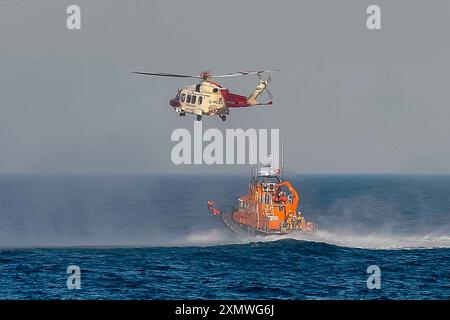 Weymouth, Dorset, Royaume-Uni. 29 juillet 2024. Le Severn Class RNLI Lifeboat RNLB Ernest and Mabel fait une exposition en soirée pour le public au large de la côte à Nothe Gardens pendant la journée de plaisir des organismes de bienfaisance pendant la semaine du bateau de sauvetage à Weymouth dans le Dorset. Un avantage supplémentaire pour les spectateurs a été l'apparition imprévue de l'hélicoptère des garde-côtes de Lee on Solent qui a treuillé un membre de l'équipage de l'hélicoptère du pont du bateau de sauvetage après qu'il a été appelé dans la région pour effectuer une fouille de la côte de Portland. Crédit photo : Graham Hunt/Alamy Live News Banque D'Images