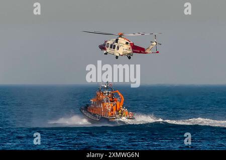 Weymouth, Dorset, Royaume-Uni. 29 juillet 2024. Le Severn Class RNLI Lifeboat RNLB Ernest and Mabel fait une exposition en soirée pour le public au large de la côte à Nothe Gardens pendant la journée de plaisir des organismes de bienfaisance pendant la semaine du bateau de sauvetage à Weymouth dans le Dorset. Un avantage supplémentaire pour les spectateurs a été l'apparition imprévue de l'hélicoptère des garde-côtes de Lee on Solent qui a treuillé un membre de l'équipage de l'hélicoptère du pont du bateau de sauvetage après qu'il a été appelé dans la région pour effectuer une fouille de la côte de Portland. Crédit photo : Graham Hunt/Alamy Live News Banque D'Images