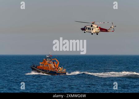 Weymouth, Dorset, Royaume-Uni. 29 juillet 2024. Le Severn Class RNLI Lifeboat RNLB Ernest and Mabel fait une exposition en soirée pour le public au large de la côte à Nothe Gardens pendant la journée de plaisir des organismes de bienfaisance pendant la semaine du bateau de sauvetage à Weymouth dans le Dorset. Un avantage supplémentaire pour les spectateurs a été l'apparition imprévue de l'hélicoptère des garde-côtes de Lee on Solent qui a treuillé un membre de l'équipage de l'hélicoptère du pont du bateau de sauvetage après qu'il a été appelé dans la région pour effectuer une fouille de la côte de Portland. Crédit photo : Graham Hunt/Alamy Live News Banque D'Images