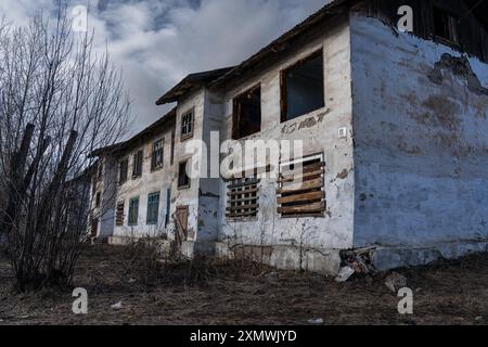 Une vieille maison abandonnée de deux étages avec fenêtres et portes arborées Banque D'Images