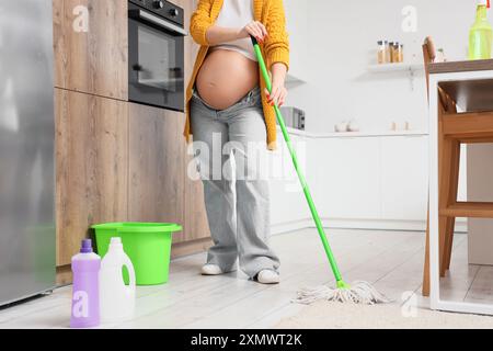 Femme enceinte nettoyant le sol dans la cuisine Banque D'Images