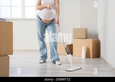 Femme enceinte nettoyant le sol dans le nouvel appartement Banque D'Images