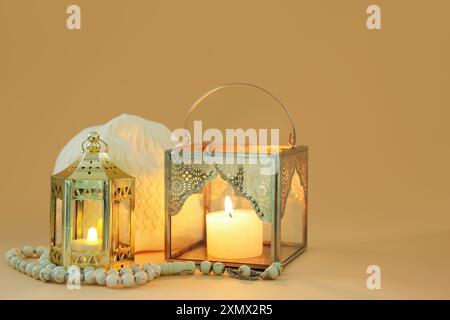 Lampes musulmanes avec des bougies allumées, des perles de prière et un chapeau sur fond de couleur Banque D'Images