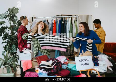 les jeunes dans les magasins d'occasion, choix de vêtements, la possibilité d'une seconde vie pour les vêtements, femme emporter les vêtements de l'autre, s'amuser Banque D'Images