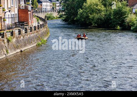 La Roche-en-Ardenne, Belgique. 4 juin 2024. Bateau à rames gonflable naviguant sur la rivière Ourthe, les bâtiments, les murs de pierre sur le bord et les arbres verts, les touristes apprécient Banque D'Images