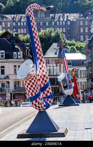 Dinant, Namur, Wallonie, Belgique. 5 juin 2024. Sculpture de saxophone peinte avec des carrés rouges et blancs, paysage urbain avec des bâtiments sur fond de flou Banque D'Images