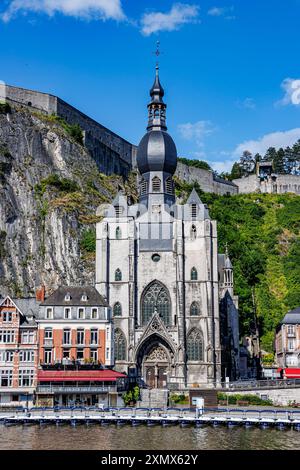 Paysage urbain avec collégiale notre-Dame de Dinant, montagne avec citadelle au sommet en arrière-plan, bâtiments face à la Meuse en station balnéaire, ensoleillé Banque D'Images