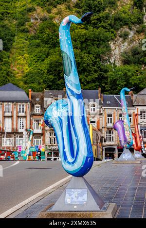 Dinant, Namur, Wallonie, Belgique. 5 juin 2024. Sculptures de saxophones, un bleu avec de petites bulles blanches au premier plan, bâtiments en arrière-plan bleu Banque D'Images