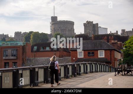 Eton, Windsor, Berkshire, Royaume-Uni. 30 juillet 2024. Une femme franchit le pont Windsor ce matin. C'était un début de journée chaleureux aujourd'hui à Eton, Windsor, Berkshire. Les températures devraient atteindre 32 degrés cet après-midi sur ce qui pourrait être le jour le plus chaud de l'année jusqu'à présent. Crédit : Maureen McLean/Alamy Live News Banque D'Images