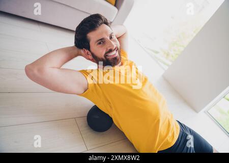 Photo de joyeux homme fort gentil portant une tenue sportive couchée mfr rouleau faisant massage à l'intérieur maison gym à domicile Banque D'Images