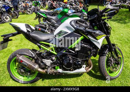 Gros plan d'une moto sportive élégante, noire et verte Kawasaki 900 garée sur l'herbe avec d'autres motos en arrière-plan. À la rencontre vélo de Calne. Banque D'Images