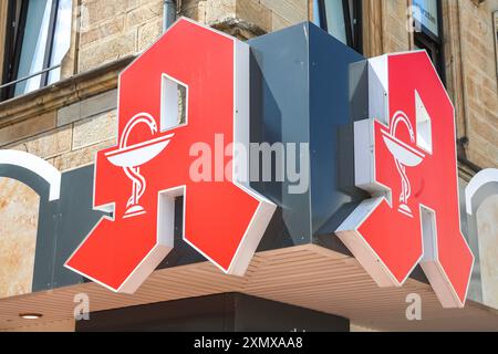 Logo an einer Apotheke. Äskulapschlange und Arzneikelch, Schale der Hygieia, Das Apotheken-A ein rotes Großes gotisches A auf weißem Grund mit in Weißer Ausführung eingezeichnetem Arzneikelch mit Schlange ist beim Deutschen Patentamt als Verbandszeichen des deutschen Apothekerverbandes DAV eingetragen. Ibbenbüren, Nordrhein-Westfalen, DEU, Deutschland, 28.06.2024 *** logo sur une pharmacie serpent esculapien et tasse de médecine, bol d'Hygieia, la pharmacie A un grand gothique rouge A sur fond blanc avec une tasse de médecine avec serpent dessiné en blanc est enregistré à l'Office allemand des brevets comme associ Banque D'Images