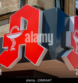 Logo an einer Apotheke. Äskulapschlange und Arzneikelch, Schale der Hygieia, Das Apotheken-A ein rotes Großes gotisches A auf weißem Grund mit in Weißer Ausführung eingezeichnetem Arzneikelch mit Schlange ist beim Deutschen Patentamt als Verbandszeichen des deutschen Apothekerverbandes DAV eingetragen. Ibbenbüren, Nordrhein-Westfalen, DEU, Deutschland, 28.06.2024 *** logo sur une pharmacie serpent esculapien et tasse de médecine, bol d'Hygieia, la pharmacie A un grand gothique rouge A sur fond blanc avec une tasse de médecine avec serpent dessiné en blanc est enregistré à l'Office allemand des brevets comme associ Banque D'Images